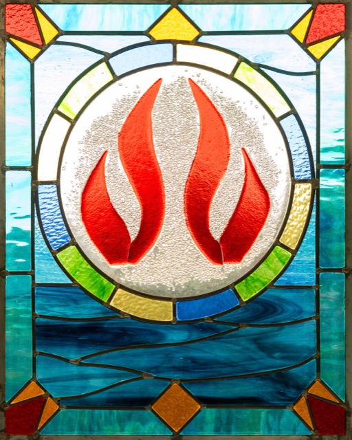 A stained-glass window of a flame, a symbol of the Holy Spirit, in our sanctuary